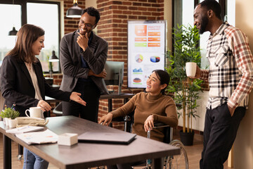 Businesswoman in wheelchair engaged in a friendly discussion with her coworkers, highlighting an...