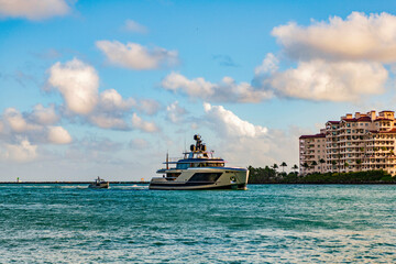 Luxury yacht boat at Fisher island. Summer vacation. Fisher island residential building and luxury yacht boat. Sunset view of Fisher island, Miami. Motor boat yacht floating to marina
