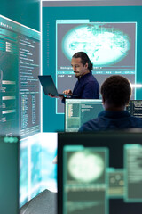 Professional hacker using ransomware and phishing tactics to compromise networks and gather intelligence for national security during cyberwarfare. Governmental spyware on big screen.