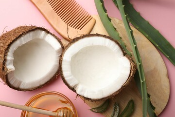 Hair treatment. Fresh coconut, honey, comb and aloe leaves on pink background, flat lay