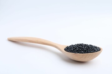 Raw lentils in wooden spoon isolated on white