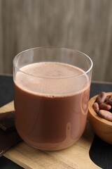Tasty chocolate milk, bars and cocoa beans on black wooden table, closeup