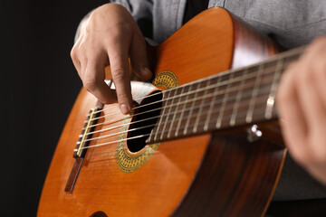 Fototapeta premium Man playing guitar on black background, closeup