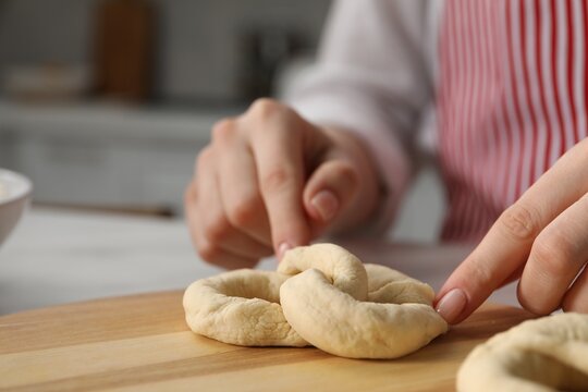 Woman shaping pretzel at table in kitchen, closeup