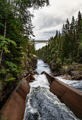 A railway bridge arches over the deep canyon of Storstupet, with rushing waters of the River Ämån...