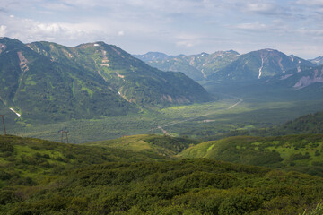 Fototapeta premium Summer mountain landscape. View from the mountains to the valley. Travel, tourism and hiking on the Kamchatka Peninsula. Beautiful nature of Siberia and the Russian Far East. Kamchatka Krai, Russia.