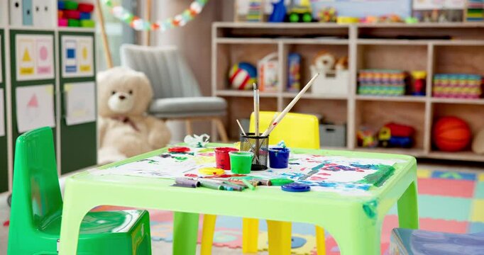 Kindergarten, art and table in empty classroom for education, learning and growth at daycare. Paint, drawing and playroom in school with toys, stationery or furniture for creative child development