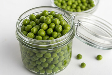 A jar of green peas is sitting on a white table