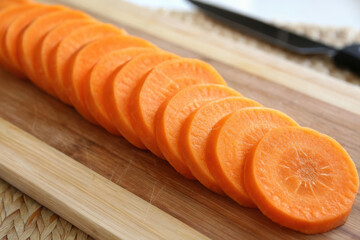 A pile of sliced carrots on a wooden cutting board