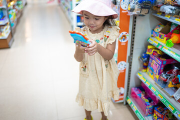 Little girl enjoy shopping toy on shelf in supermarket