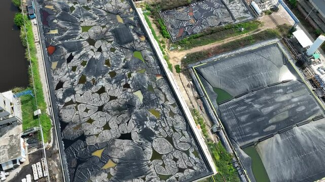 The site displays mixed containment conditions, active sludge ponds with compromised linings and a newer section ready for use or recently drained.
