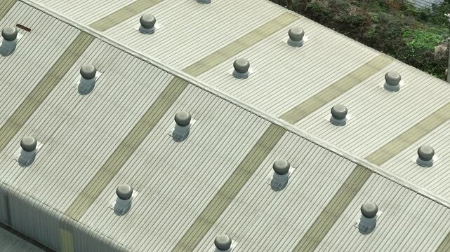 Energy-efficient roofing design featuring turbine ventilators and skylights supports natural ventilation and reduces reliance on artificial lighting.
