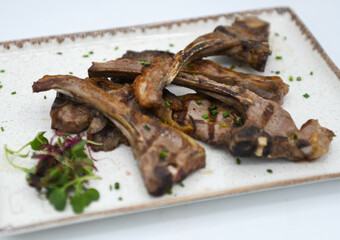 Costillas de cordero a la parrilla con hierbas frescas y especias en un plato blanco