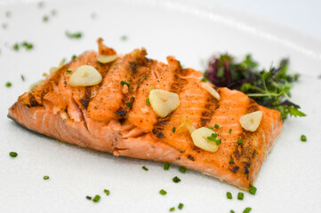 Filete de salmón con ajo y hierbas en un plato blanco.