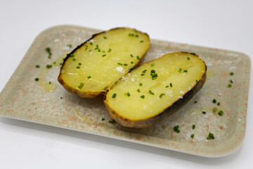 Patatas al horno con ajo y sal en un plato sobre fondo blanco.
