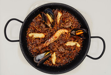 Paella de marisco en una sartén sobre un fondo blanco
