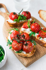 Bruschetta with cottage cheese, arugula and roasted cherry tomatoes. Food photo.