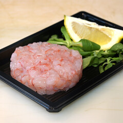 tartare di gamberi servito in un piattino di plastica con limone