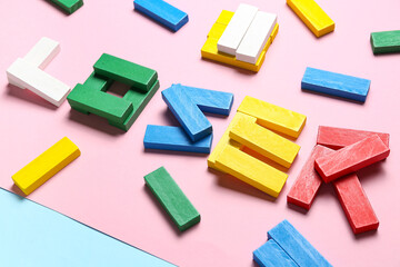 Word LOOSER made of colorful blocks on pink background, closeup