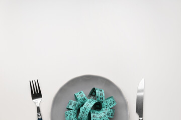 Table setting with measuring tape on light background, closeup