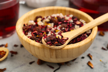 Bowl and spoons with dried fruit tea on grey grunge table, closeup