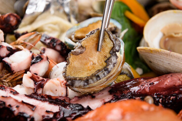 Lifting an abalone from a seafood stew
