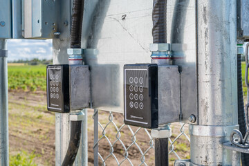 Two black boxes with a keypad on them are attached to a metal pole