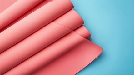 Obraz premium Overhead view of coral pink eco-friendly yoga mat arranged diagonally across frame, matte finish contrasting against powder blue seamless backdrop, cinematic lighting emphasizing material textures,