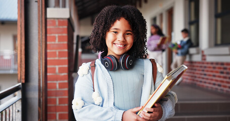 Portrait, school and girl with book, student and pride with education, child development and growth. Face, outdoor and happy kid with knowledge, academy and confidence with smile and scholarship