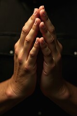 Close-up of two hands in a prayer position, symbolizing peace and reflection against a dark backdrop