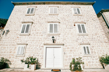 Antique stone apartment building with white wooden closed shutters