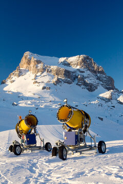 Two snow cannons on a ski slope in the alps, Dolomites, Italy