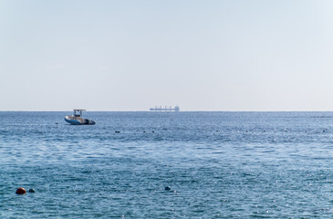 Calm blue sea with the silhouette of a large ship on the horizon