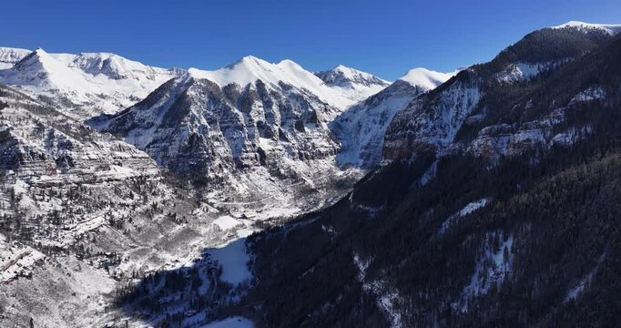 An unworldly aerial drone shot of the extreme Kroger Via Ferrata cliff face and the Black Bear pass switchbacks and summit, slowly tracking forward over the Telluride Valley floor in Western Colorado.