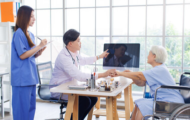 Asian male doctor and caring nurse holding a clipboard talking to old woman patient about ways of...