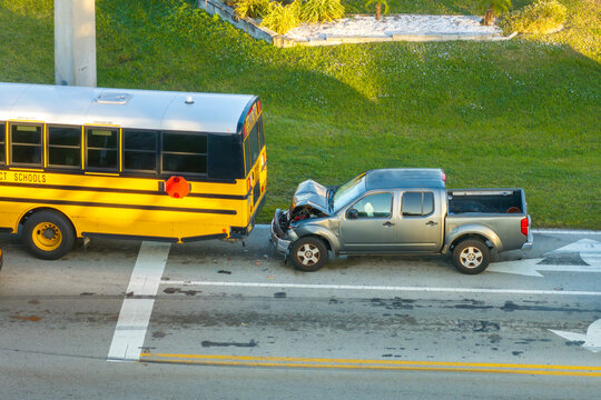 First responders responding to school bus and car accident site on American street. Emergency services helping victims of vehicle crash on road in USA