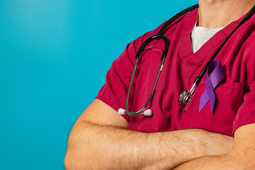 Healthcare professional wearing purple ribbon on scrubs during daytime