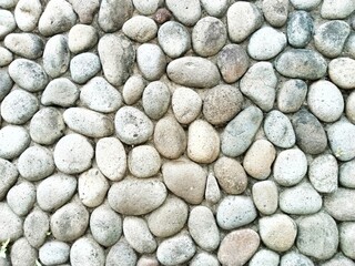 The background and surface texture of the wall are made of river stones with round, oval, and oblong shapes and varying sizes.