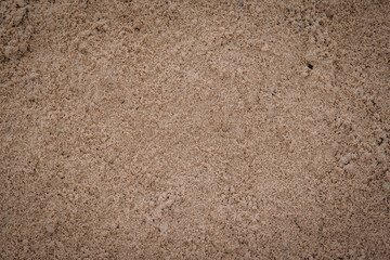 Close-up of loose, dry brown construction sand forming a fine-grained, natural textured surface, ideal for background or material concepts..