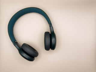 Large green headphones with soft earbuds and a soft headband lie on the left side of the image on a beige background