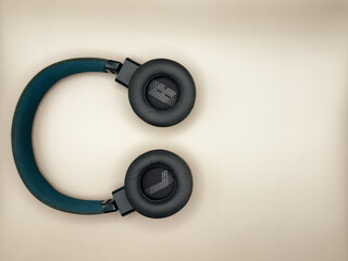 Headphones are full-size, large, green, with soft earphones turned outward, in which the left and right earphones are indicated, and a soft bow lies on the left with images on a beige background