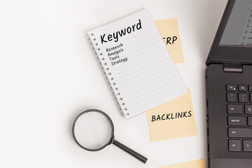 A notebook with the word Keyword, Research, Analysis, Tools, and Strategy, with sticky notes labeled Backlinks, a magnifying glass, and a laptop. Ideal for keyword planning or SEO concepts.