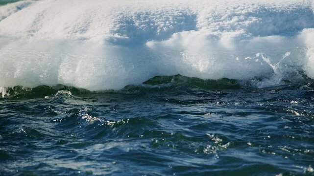 Experience the tranquil beauty of majestic icebergs interacting with the ocean, as gentle waves lap against stunning icy formations, showcasing the serene beauty of nature in this mesmerizing footage