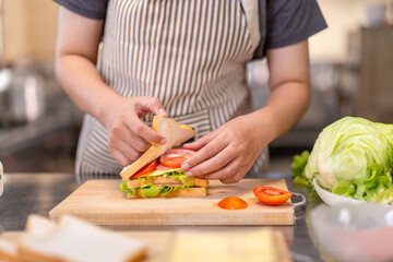 Close-Up of Chef Preparing a Fresh Sandwich with Cheese and Vegetables