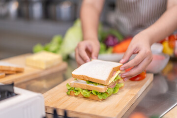 Hands Assembling a Fresh Sandwich on Wooden Cutting Board