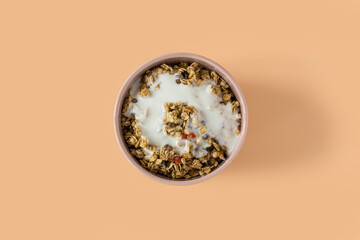 Granola with yogurt . Side view of a ceramic bowl with granola  and yoghurt on the beige background . Muesli with dried fruit close-up . 