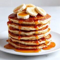 Stack of pancakes with banana slices and syrup isolated on white background