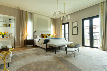 Spacious master bedroom with large area rug, wood floor, white ceiling lamp and several windows.