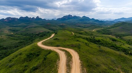 Fototapeta premium Aerial View of Winding Dirt Road Surrounded by Lush Green Hills and Mountains : Generative AI