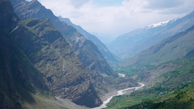 4K Landscape shot of river Chandrabhaga flowing in between the Himalayan mountain peaks at Pattan Valley as seen from Marbal Village in Lahaul, Himachal Pradesh, India. Scenic view of river in valley.